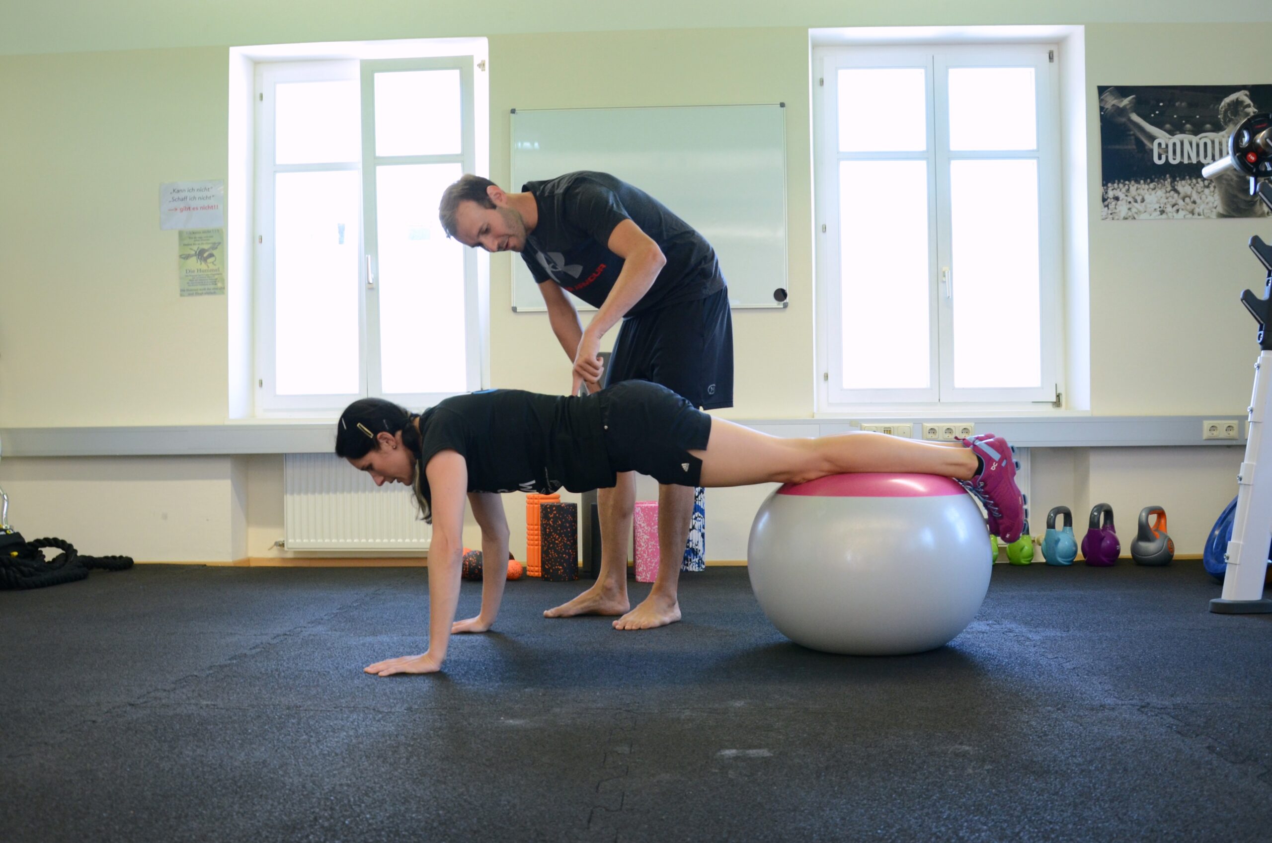 Florian Berlinger korrigiert eine Kundin beim Plank am Ball im Personal Training